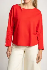 Sweater rojo de algodón con textura y corte oversize. Tiene mangas largas con dos rayas blancas en los brazos.