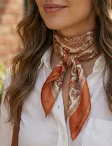 Pañuelo cuadrado de satén con estampado de arabescos en tonos terracota, blanco y marrón.