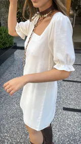 Vestido corto blanco de corte evasé, con escote cuadrado y mangas cortas abullonadas.