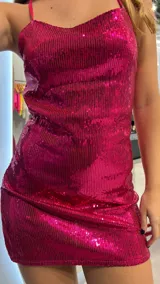 Vestido corto fucsia con lentejuelas, espalda descubierta y tirantes finos.