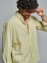 Camisa de manga larga color amarillo claro con rayas verticales blancas, cuello abotonado y bolsillo en el pecho.