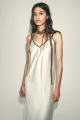 Vestido largo color blanco hueso de satén, con escote en V y tirantes finos negros ajustables en la espalda.
