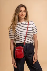 Bandolera compacta de símil cuero color rojo, con correa regulable y desmontable. Posee apertura superior, bolsillo frontal con cierre y bolsillo trasero abierto.