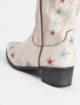 Botas tejanas de cuero vegano color crema con bordados de estrellas rojas y azules.