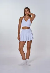 Conjunto deportivo blanco compuesto por top con breteles finos y falda corta tableada.