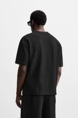 Camiseta negra de corte holgado, con cuello redondo y mangas cortas.