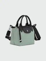 Bolso Longchamp modelo Le Pliage Energy XS, color verde agua con detalles en negro. Cuenta con doble asa corta, correa de hombro ajustable y extraíble, cierre con broche a presión y cordón decorativo.