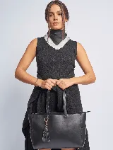 Bolso tipo tote de cuero sintético color negro con doble asa de hombro, cierre superior y doble compartimento interno. Incluye un dije colgante de borla.