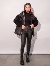 Campera de nylon negra con textura capitoneada y mangas de corderito, con capucha y cierre central.