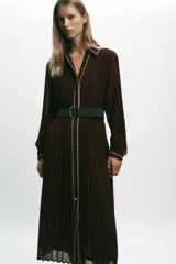 Vestido midi marrón chocolate plisado, con cuello solapa, manga larga y cinturón. Presenta cierre frontal con botones y vivos blancos a contraste en cuello, mangas y botonera. Incluye forro interior.