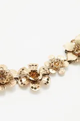 Cinturón plateado de metal con cadena de eslabones y apliques de flores.