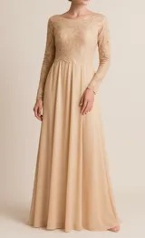 Vestido largo color crudo, con cuerpo de encaje y falda de gasa. Tiene mangas largas y escote redondo.