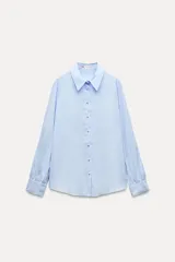Camisa marrón de corte holgado, con cuello de solapa, manga larga con pliegues y bajo asimétrico. Cierre frontal con botones.