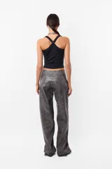 Pantalón de cuerina gris con estampado abstracto, corte recto y tiro medio. Presenta cierre metálico, botón tipo broche y bolsillos laterales.