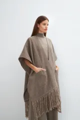 Ruana color crema de lana fina con flecos en el ruedo y bolsillos delanteros.