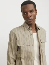 Sobrecamisa beige de manga larga con cuello clásico y fit cómodo. Confeccionada en tejido de sarga resistente de algodón y lino, con cierre con botones y bolsillos en el pecho con cierre de botón.