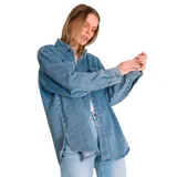 Camisa de jean celeste, de corte amplio, con cuello clásico, cierre frontal con botones, mangas largas con puños abotonados, dos bolsillos con solapa abotonada en el pecho y aberturas laterales en el ruedo.