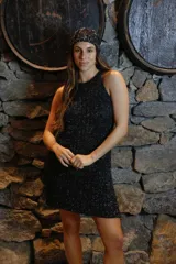 Vestido corto tejido con hilo de algodón y lurex en punto perlado, color negro con brillos plateados. Cuello halter y silueta holgada.