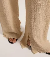 Pantalón largo color beige, de poliéster texturizado, con cintura elástica y bolsillos laterales.