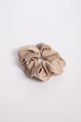 Gomita de pelo tipo scrunchie color beige confeccionada en tela satinada.