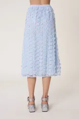 Falda midi de tul celeste bordada con flores y lentejuelas. Tiene forro de tejido tipo cuadros vichy con calados transparentes, cintura elástica y corte recto, ligeramente acampanado en el bajo.