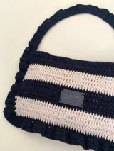 Cartera tejida a crochet con hilo 100% de algodón, con diseño a rayas y volados bordeando la cartera extendiéndose hacia la manija.