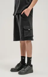Bermuda negra de algodón rústico con calce oversize, elástico en la cintura y bolsillos con cierre.