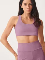 Top deportivo color malva, de corte cuadrado y tirantes anchos, diseñado para actividades físicas.