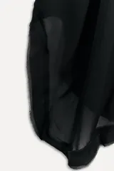 Vestido tipo capa color negro confeccionado en hilatura de viscosa, con escote pico, manga corta y bajo asimétrico desflecado.
