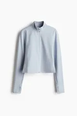 Campera deportiva corta celeste con cuello alto, cierre frontal, mangas largas con orificios para los pulgares y tecnología SoftMove™ y DryMove™.