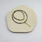 Collar elaborado con mini cuentas facetadas de turmalina multicolor y un dije colgante en forma de flecha dorada con incrustaciones de cristales.