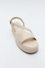 Sandalia marrón con plataforma, tiras cruzadas y pulsera ajustable.