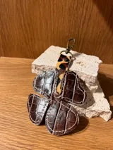 Llavero de cuero rojo con forma de trébol de cuatro hojas y gancho metálico color bronce.