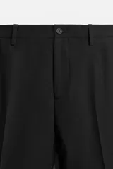 Pantalón de vestir negro slim fit, confeccionado en tejido con viscosa. Cuenta con bolsillos frontales y traseros de vivo. El cierre es frontal con cremallera y botón.