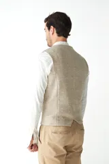 Chaleco de vestir para hombre, color marrón claro con textura tweed. Diseño sastrero con cuello en V, cierre frontal con botones, bolsillos ribeteados y forro interno. Confeccionado en lana fina sin teñir, diseñado exclusivamente por Don Baez.
