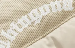 Campera puffer marrón con parte superior de pana y bordado blanco en la espalda con la palabra "Chingona". Tiene tiras regulables en la cintura.