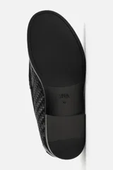 Mocasín de cuero negro con diseño trenzado en la parte superior, horma redonda y suela con ligero tacón.