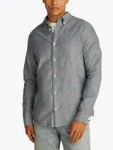 Camisa de manga larga Tommy Jeans, confeccionada en algodón y lino color gris jaspeado. Tiene cuello abotonado, cierre con botones, corte regular y logo bordado en el pecho.