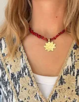 Collar corto de piedras de coral rojo irregulares con dije de bronce dorado en forma de sol martillado.