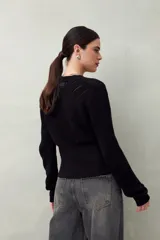 Sweater negro de tejido de punto calado, con escote en V cruzado y mangas largas.