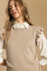 Top tejido sin mangas color negro, con cuello redondo y volados en las sisas con terminación en contraste de punto blanco. Presenta un calce recto y puño inferior acanalado con detalle de punto blanco.