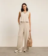 Conjunto deportivo de dos piezas color beige con finas rayas verticales negras. Incluye un chaleco corto con cuello en V y un pantalón palazzo con cintura elástica ajustable.