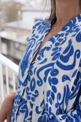 Vestido largo de corte holgado con estampado floral en tonos azul y blanco. Tiene cuello en V, mangas largas y falda con volantes.