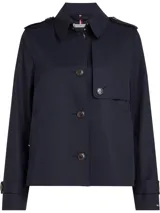 Gabardina corta azul marino de Tommy Hilfiger, con botonadura simple, cuello inglés, trabillas en los hombros, solapa de protección delantera y trasera, puños con tira y botón, y logo metálico en el puño.