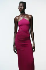 Vestido color fucsia de poliamida con cuello halter con lazada y detalle de aplicación metálica en forma de sol.