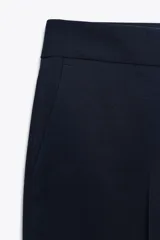 Pantalón de vestir azul marino, de corte recto, con bolsillos laterales y traseros. Se ajusta a la cintura con cierre frontal con cremallera y gancho metálico.