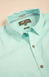 Camisa amarilla de algodón orgánico, manga larga con botones de madera, cuello italiano, calce regular, bolsillo de pecho con logo bordado.