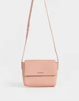 Bandolera color beige de cuerina con solapa, tag metálico y correa larga regulable.
