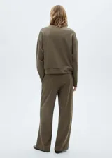 Pantalón de jogging color verde oliva, de corte ancho y tiro medio, con cintura elástica ajustable con cordón. Presenta costuras verticales decorativas en el frente y bolsillos laterales.