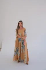 Vestido largo color camel con estampado de flores azules, corte amplio, escote en V y mangas 3/4.